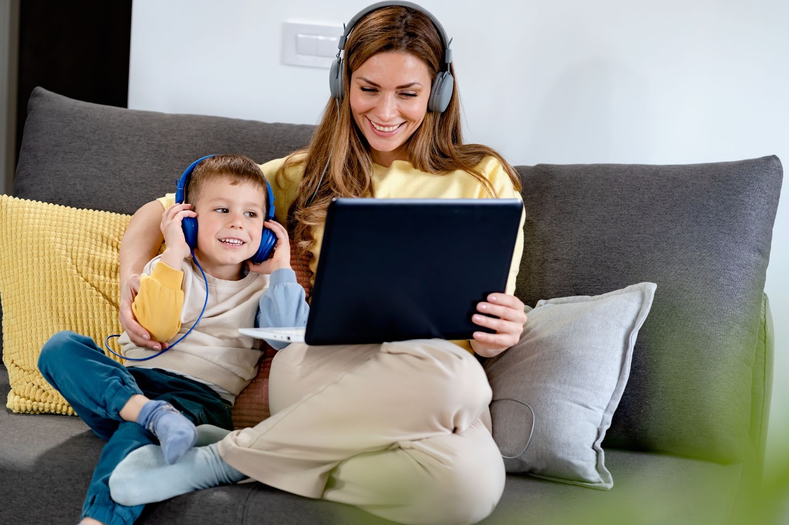 Mère souriante et son fils écoutant ensemble un podcast sur un ordinateur portable. Utiliser la technologie pour l'éducation.