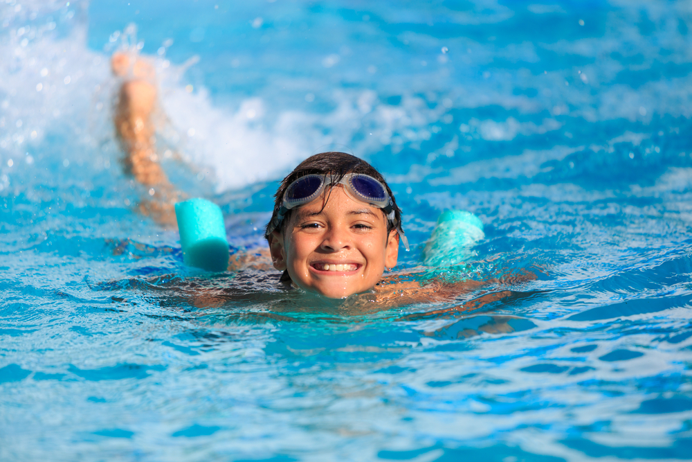 enfant souriant qui nage dans une piscine, activité sportive, activité extrascolaire