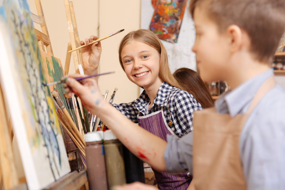 fille souriante en train de peindre dans un cours de peinture