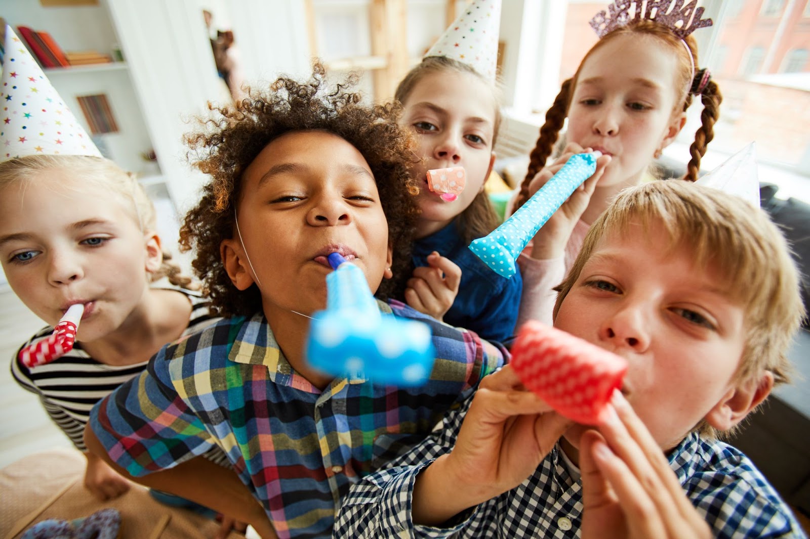 enfants soufflant dans des sifflets cotillon pour un jeu d’anniversaire