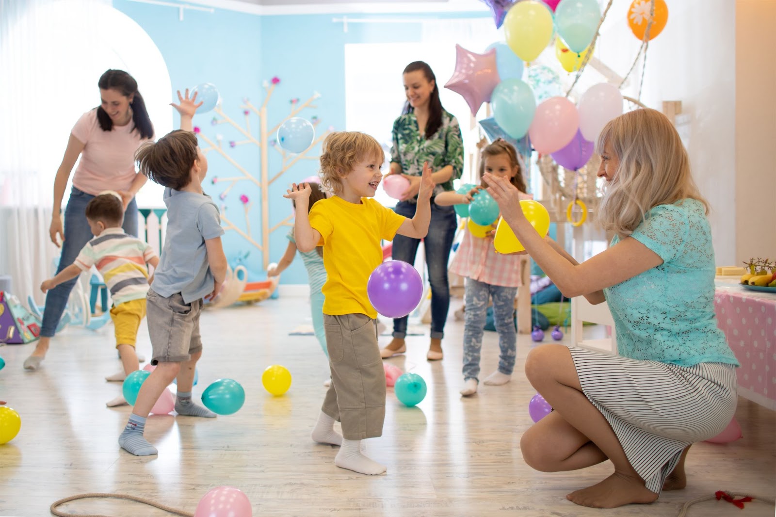 enfants et adultes jouant ensemble avec des ballons pour un anniversaire en intérieur