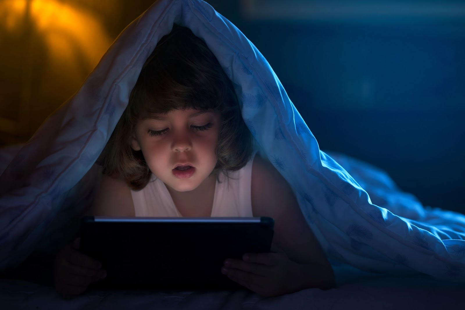 Gros plan sur un petit garçon regardant des dessins animés sur la tablette numérique la nuit avec espace pour copie