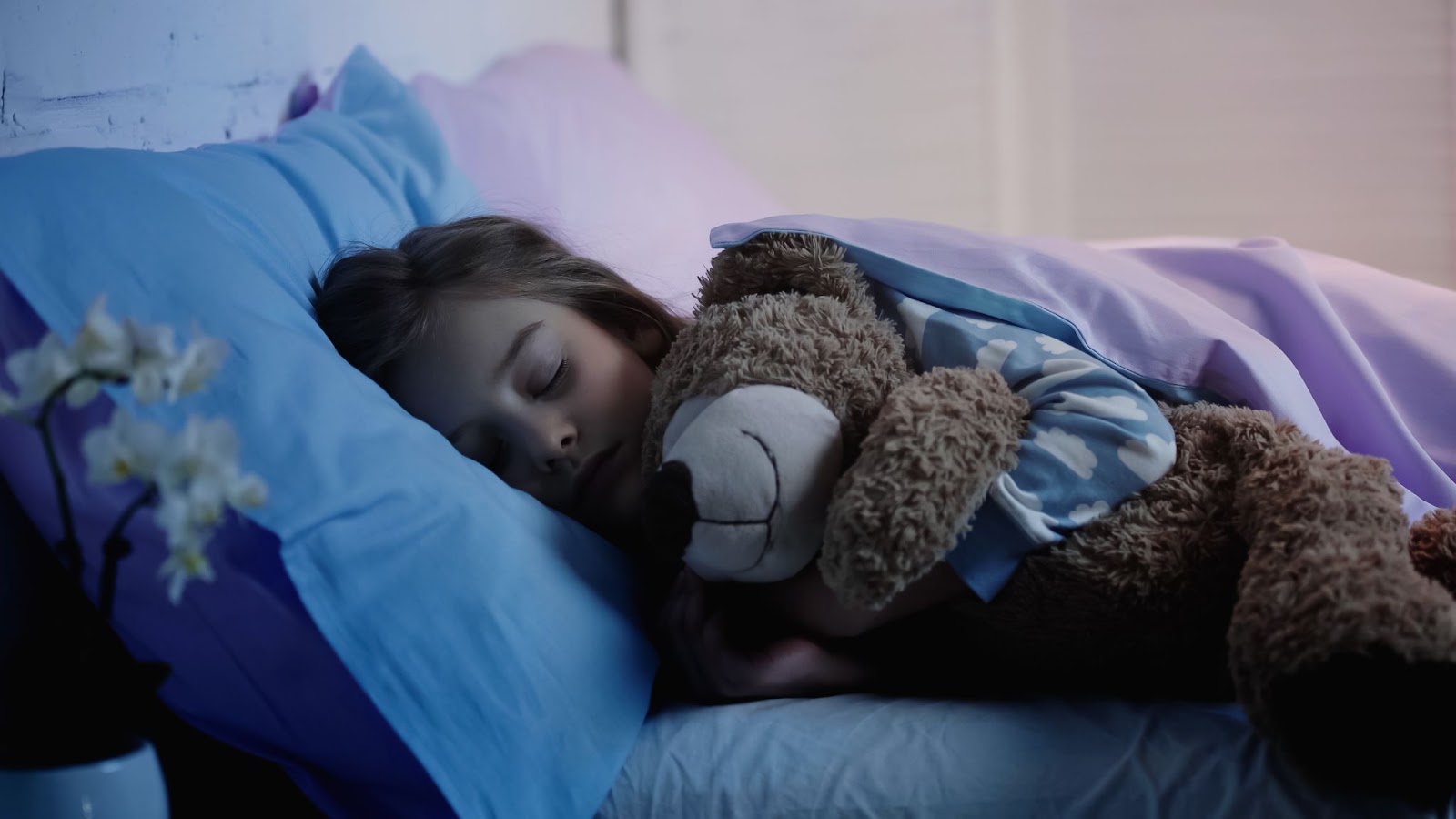 fille qui serre son doudou dans son lit en dormant